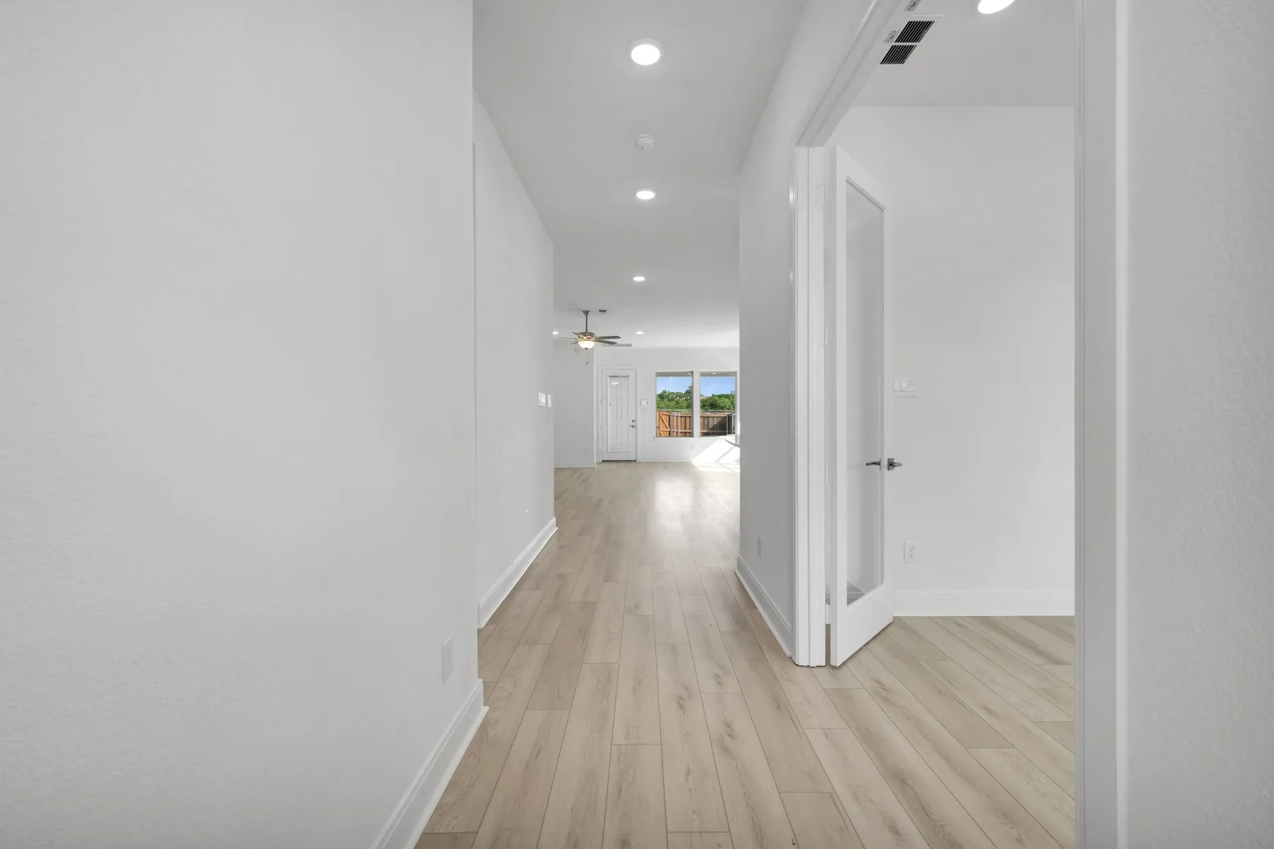 Hall with light wood finished floors and recessed lighting