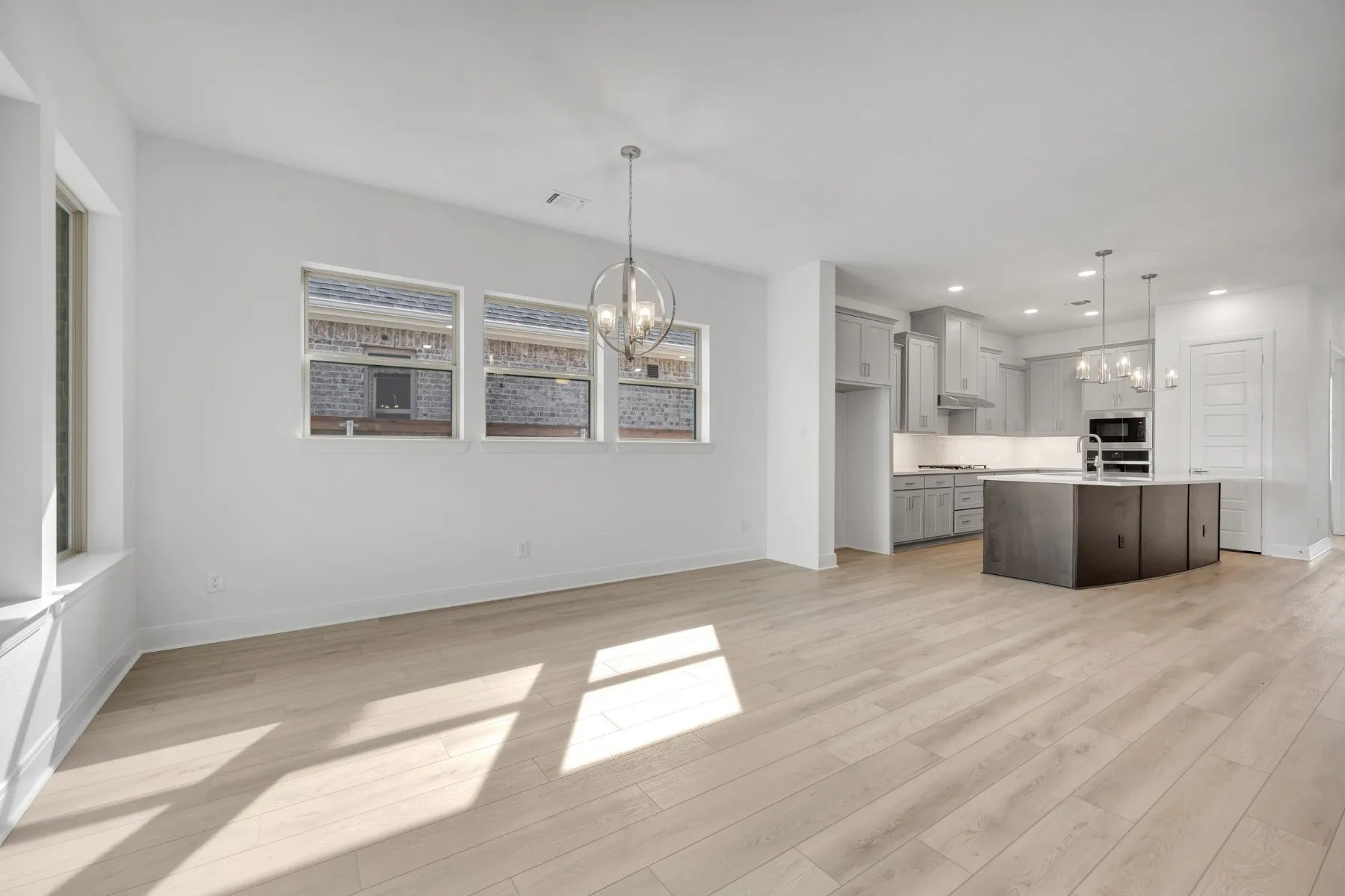 Kitchen featuring a chandelier, light wood finished floors, and a kitchen island with sink