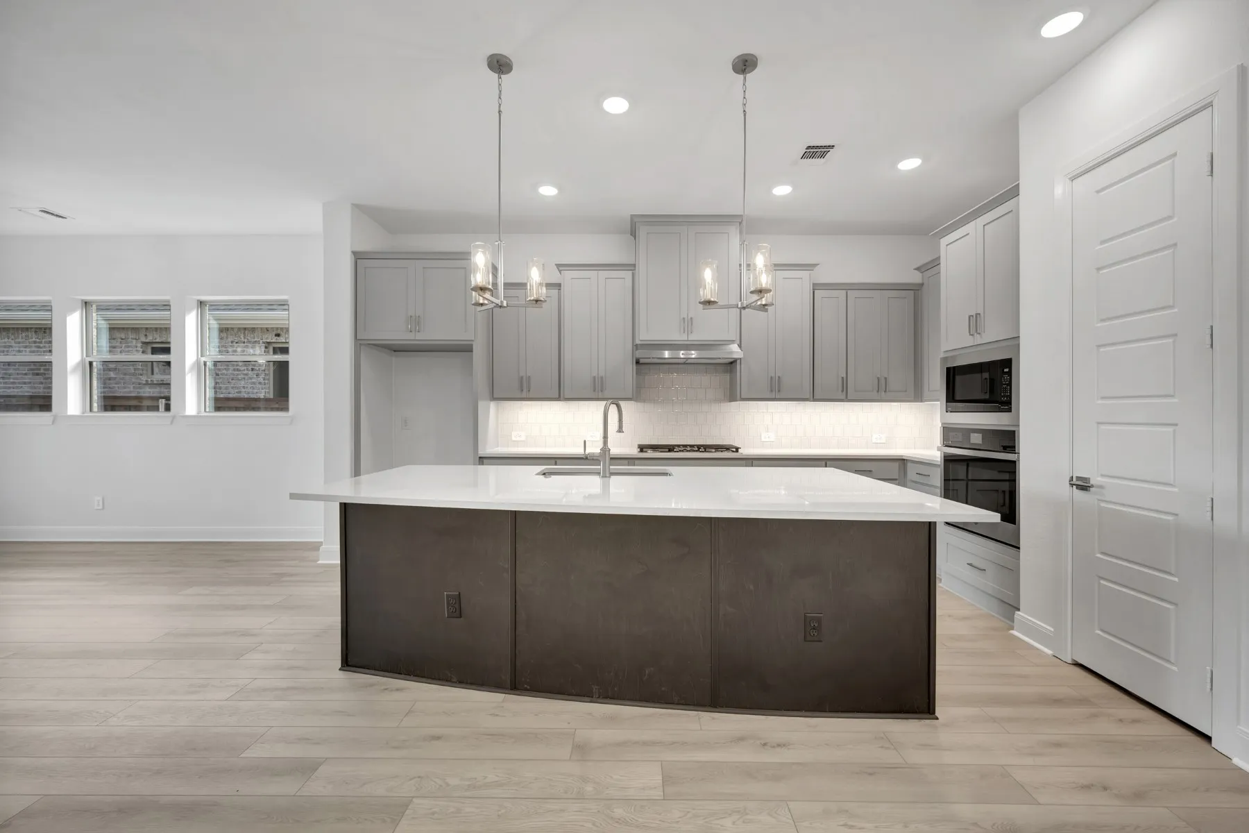 Kitchen with gray cabinets, light wood finished floors, and a center island with sink