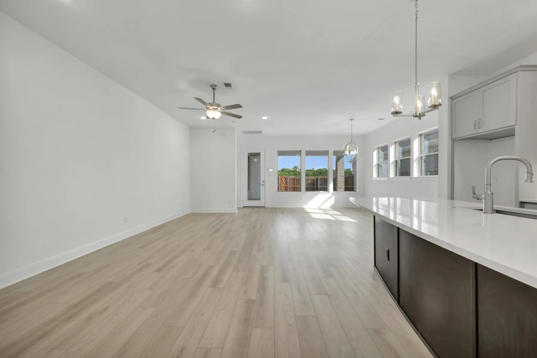 Kitchen featuring open floor plan, light wood finished floors, hanging lights, ceiling fan, and dark wood finish cabinets