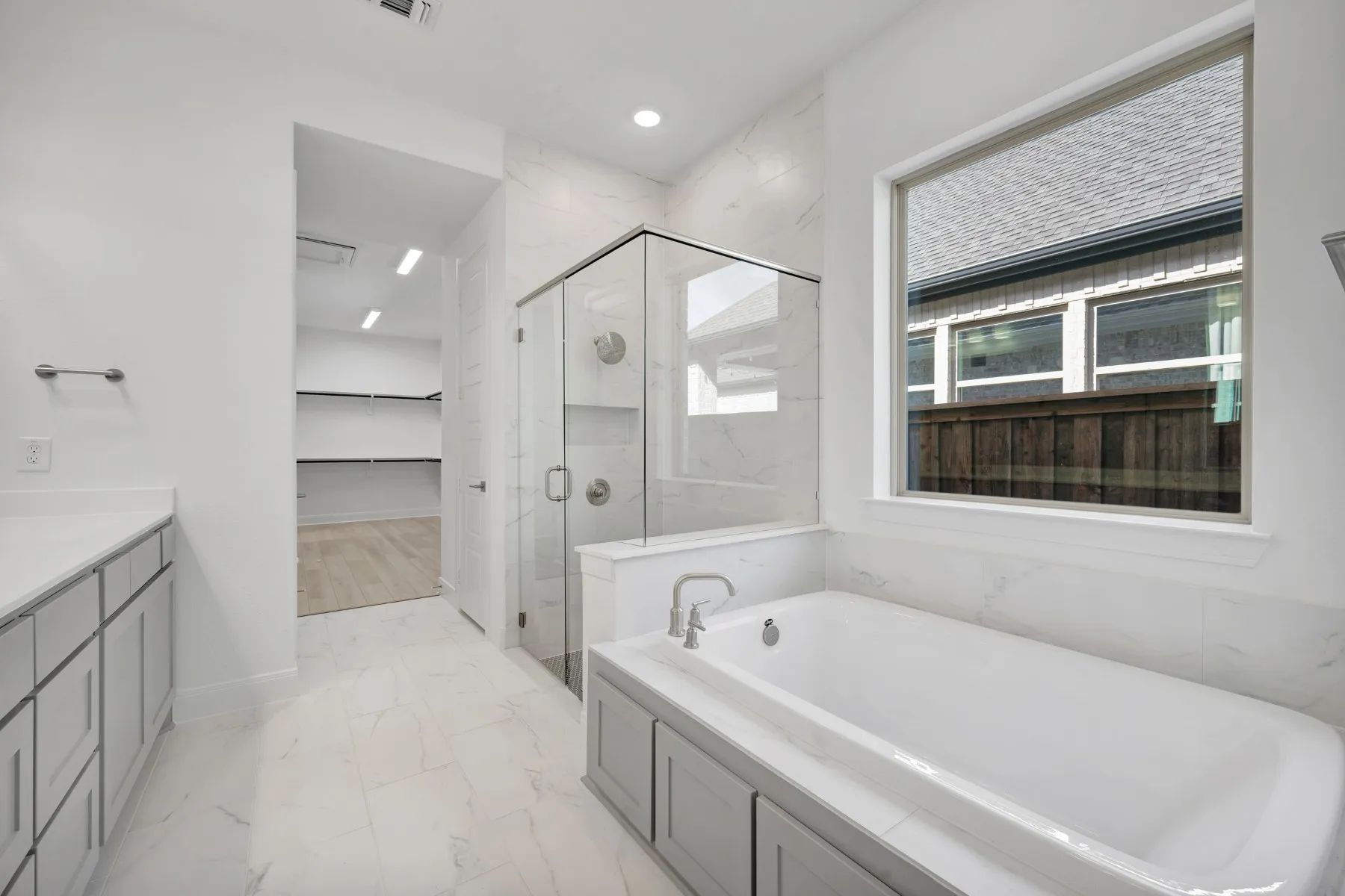 Bathroom featuring a spacious closet, a marble finish shower, light marble finish floors, vanity, and a bath