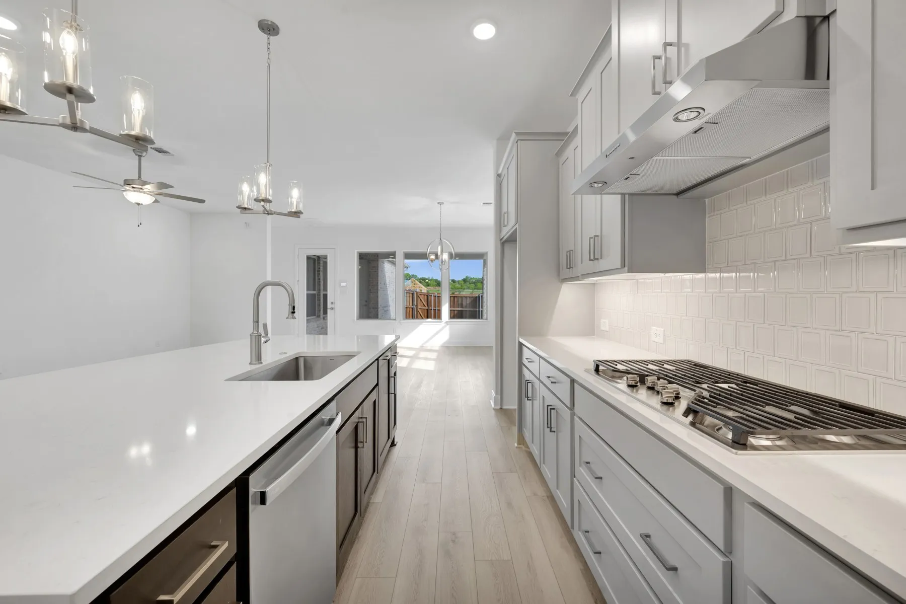 Kitchen featuring hanging lights, a ceiling fan, stainless steel appliances, light wood-style flooring, and light stone counters