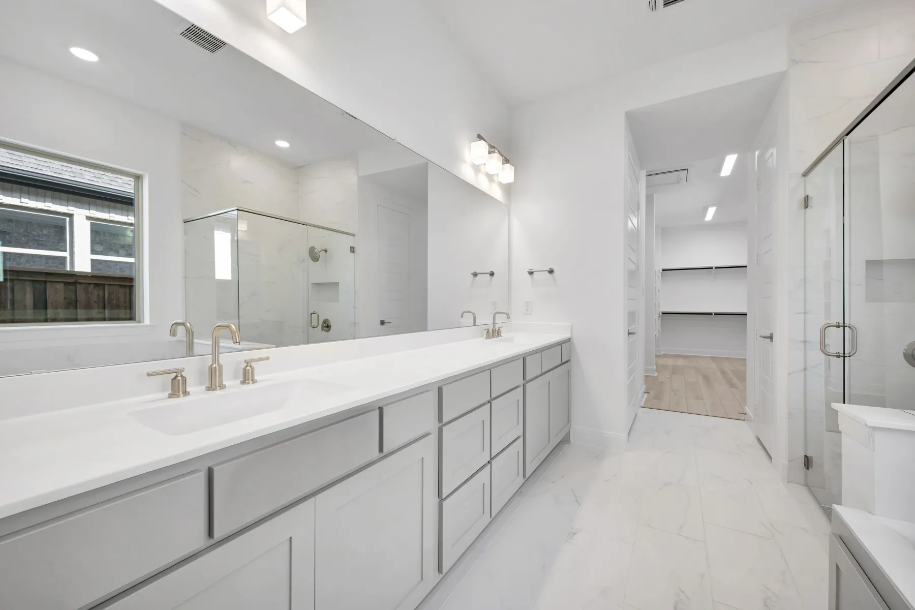 Full bathroom featuring double vanity, a marble finish shower, a spacious closet, and light marble finish flooring