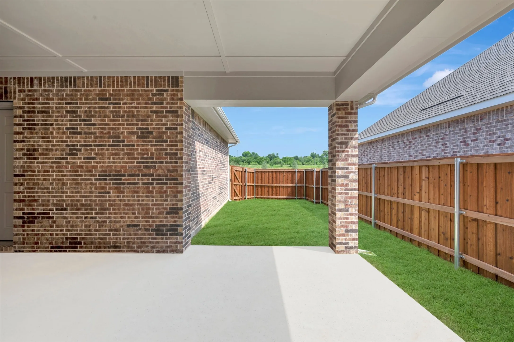Covered patio featuring a concrete surface, a brick column, and a painted ceiling