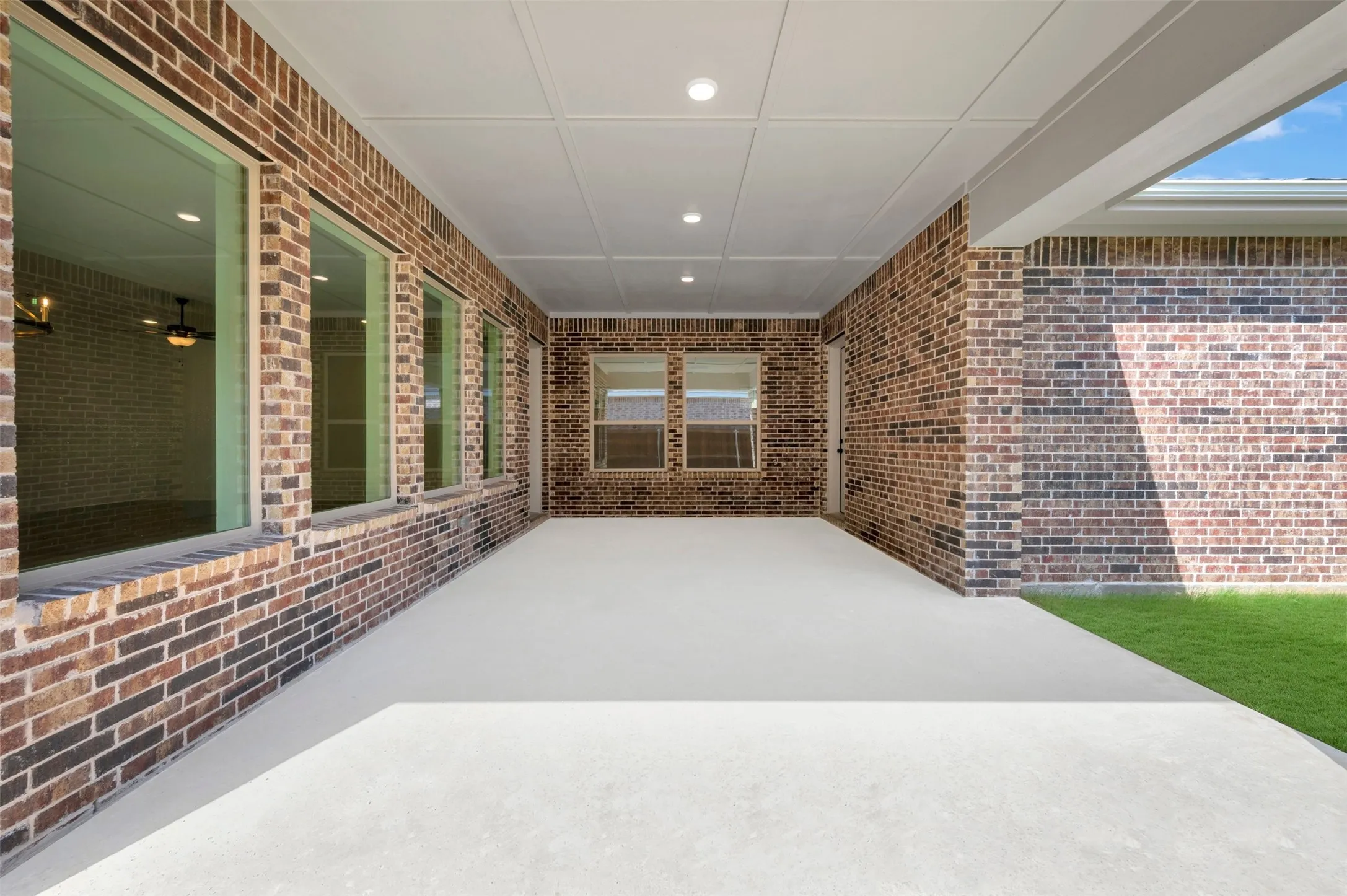 Covered patio featuring a concrete surface, recessed lighting, and brick exterior walls