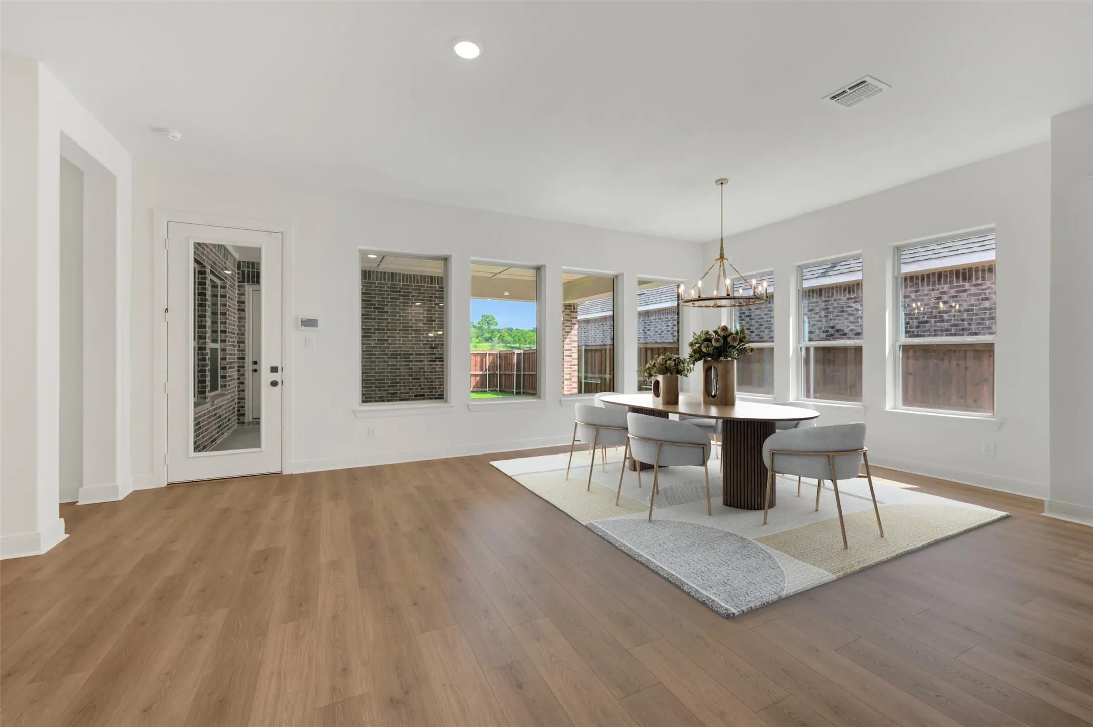 Spacious dining area featuring wood-finish flooring, ample natural light from multiple windows, and recessed lighting