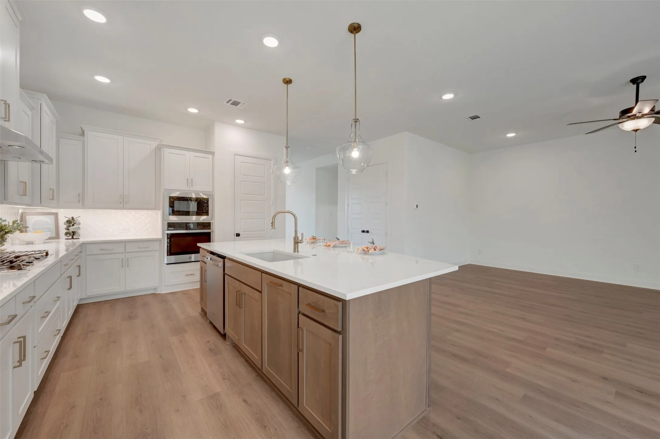 Expansive kitchen featuring white cabinetry, light countertops, and wood-finish flooring