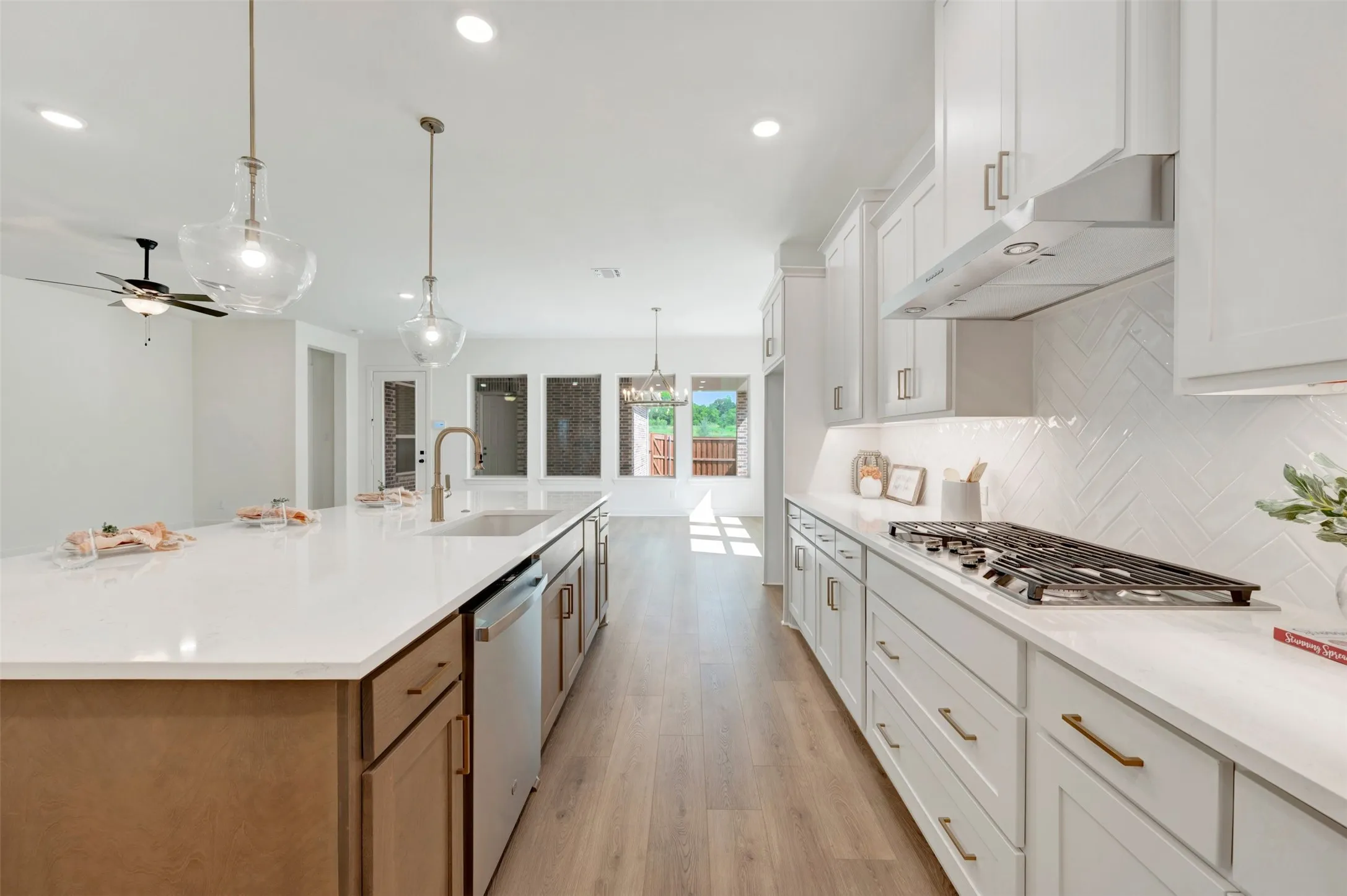 Open-concept kitchen featuring an expansive island with a built-in sink, stainless steel appliances, and pendant lighting