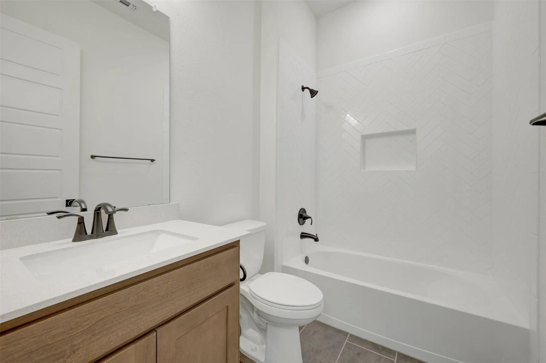 Bathroom featuring a wood-finish vanity with an integrated sink and light-toned countertop