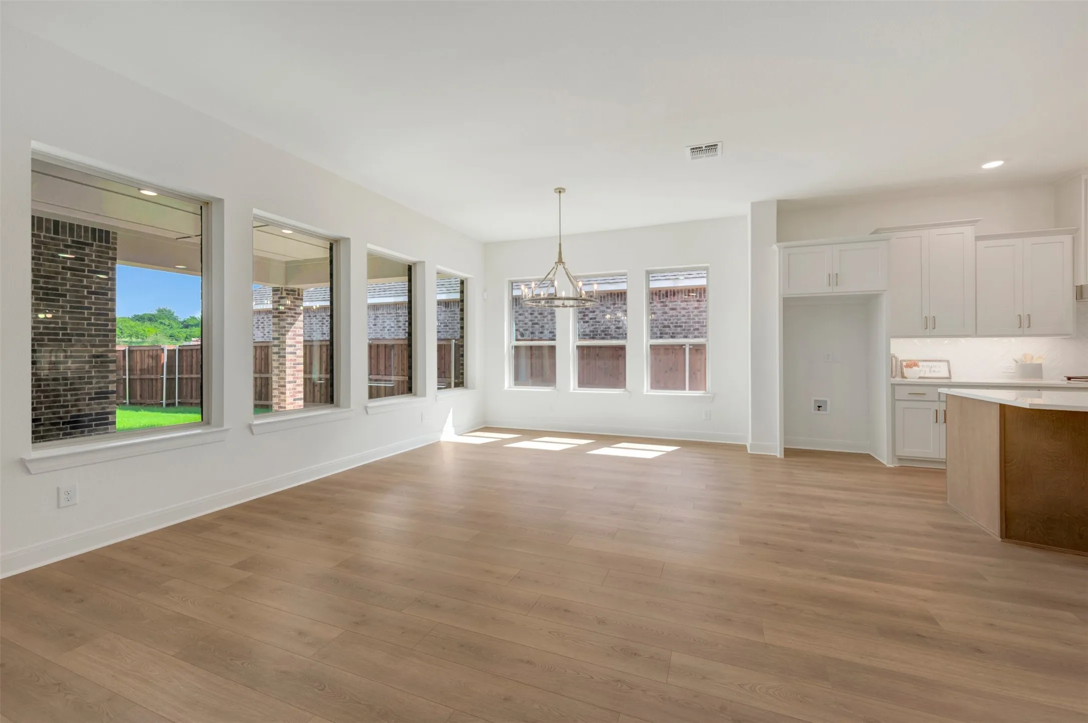 Open-concept living space featuring wood-finish flooring, white walls, and multiple windows