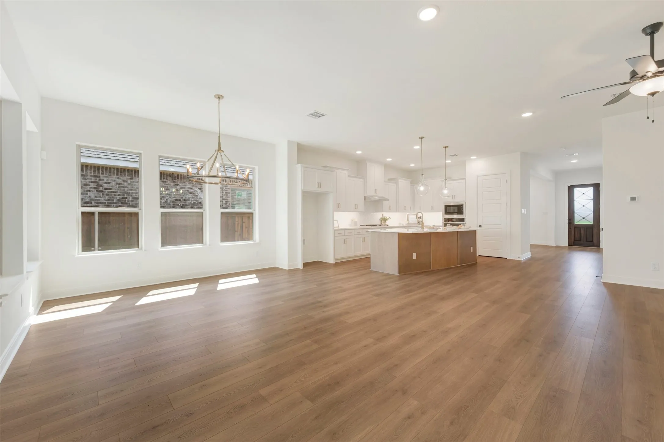 Spacious open-concept interior featuring wood-finish flooring, recessed lighting, and a modern kitchen with a large island