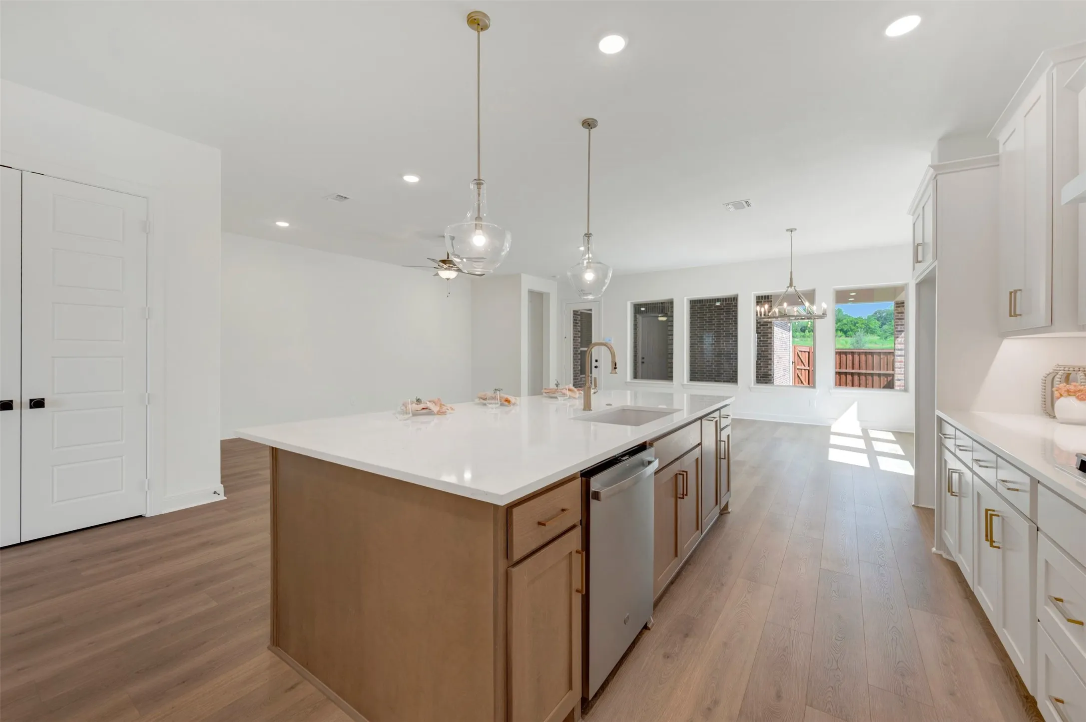 Expansive kitchen island featuring a white countertop, undermount sink, and integrated dishwasher