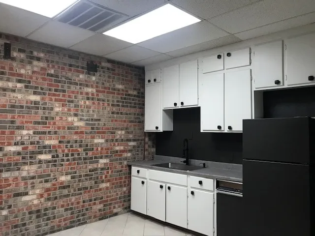 Kitchen with white cabinetry, a paneled ceiling, black refrigerator, sink, and light tile flooring