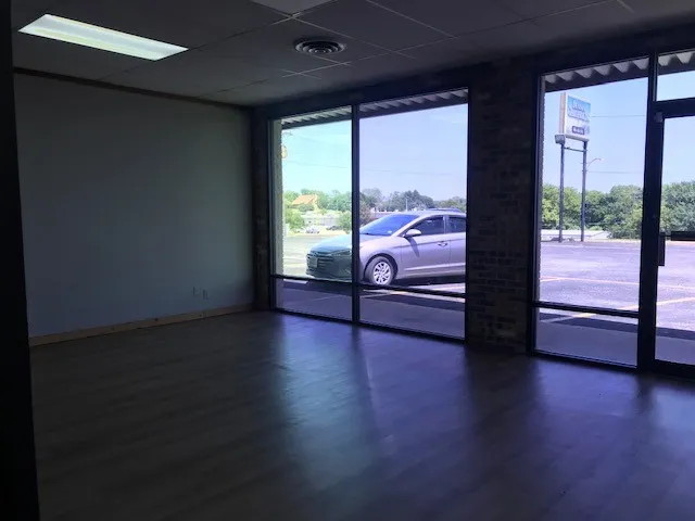 Empty room with floor to ceiling windows, dark wood-type flooring, and a drop ceiling