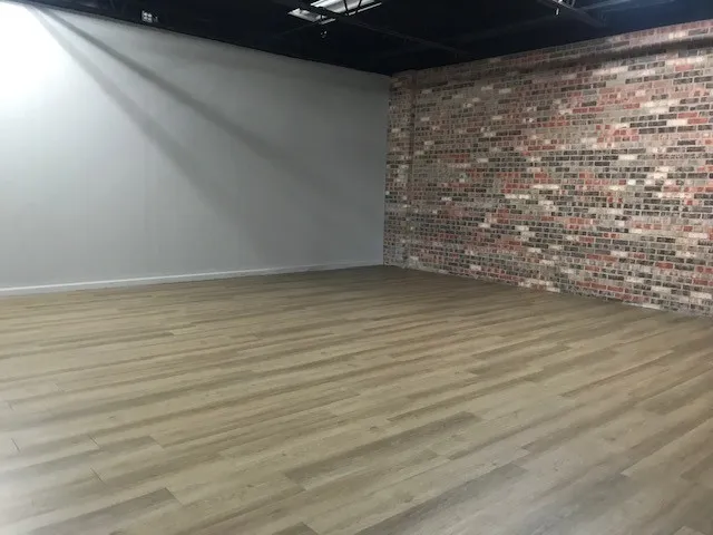 Empty room featuring hardwood / wood-style floors and brick wall