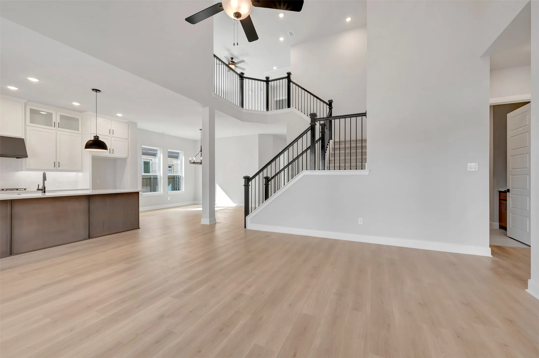 Unfurnished living room featuring recessed lighting, ceiling fan, light wood finished floors, and a high ceiling