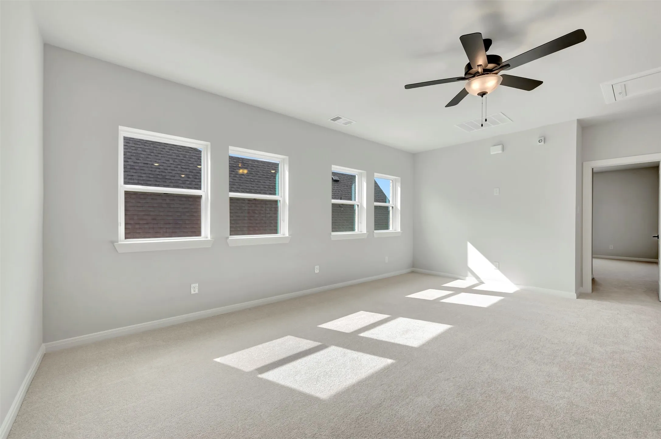 Empty room featuring light colored carpet and ceiling fan