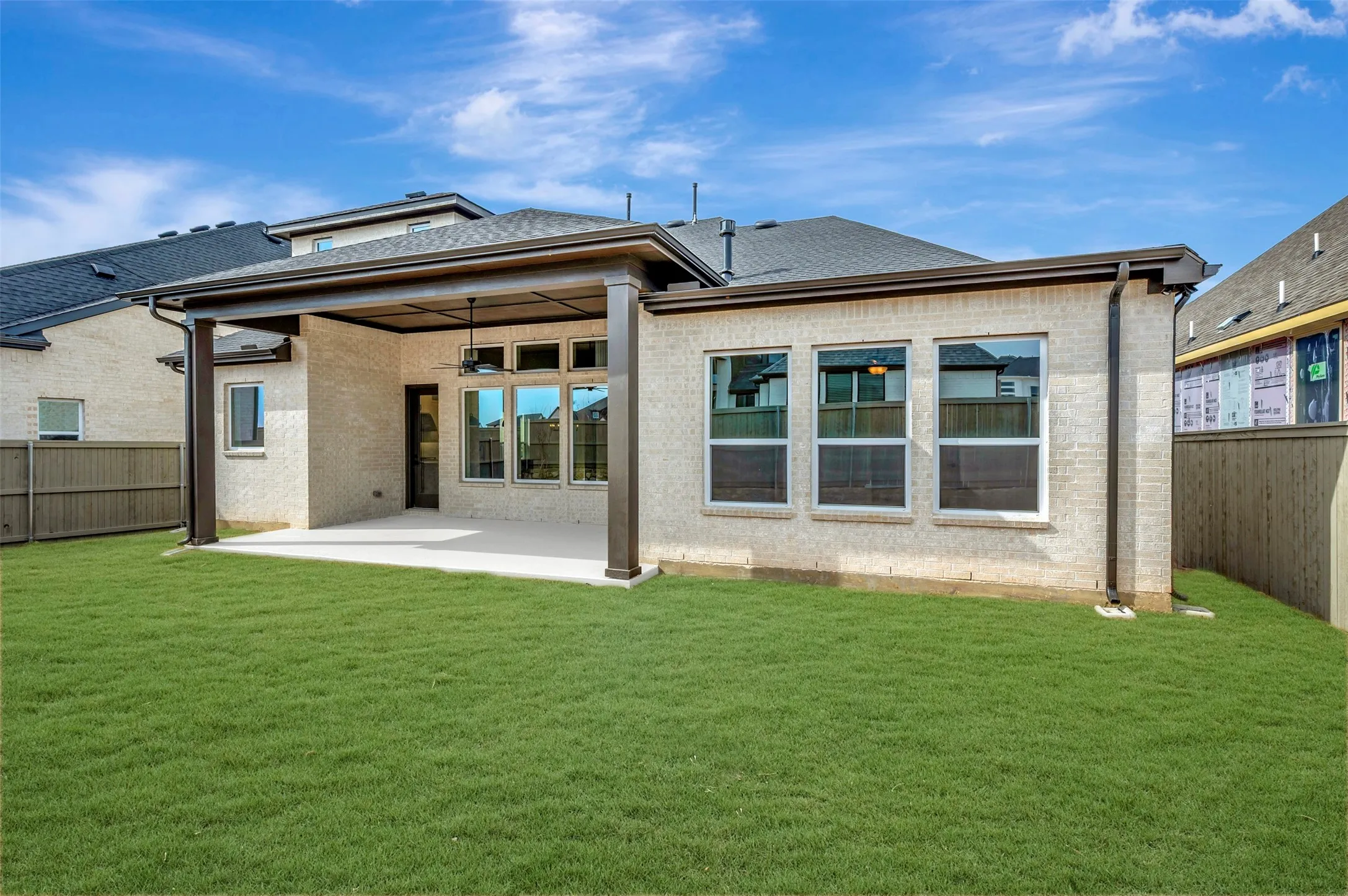 Back of property with a fenced backyard, brick siding, and a patio