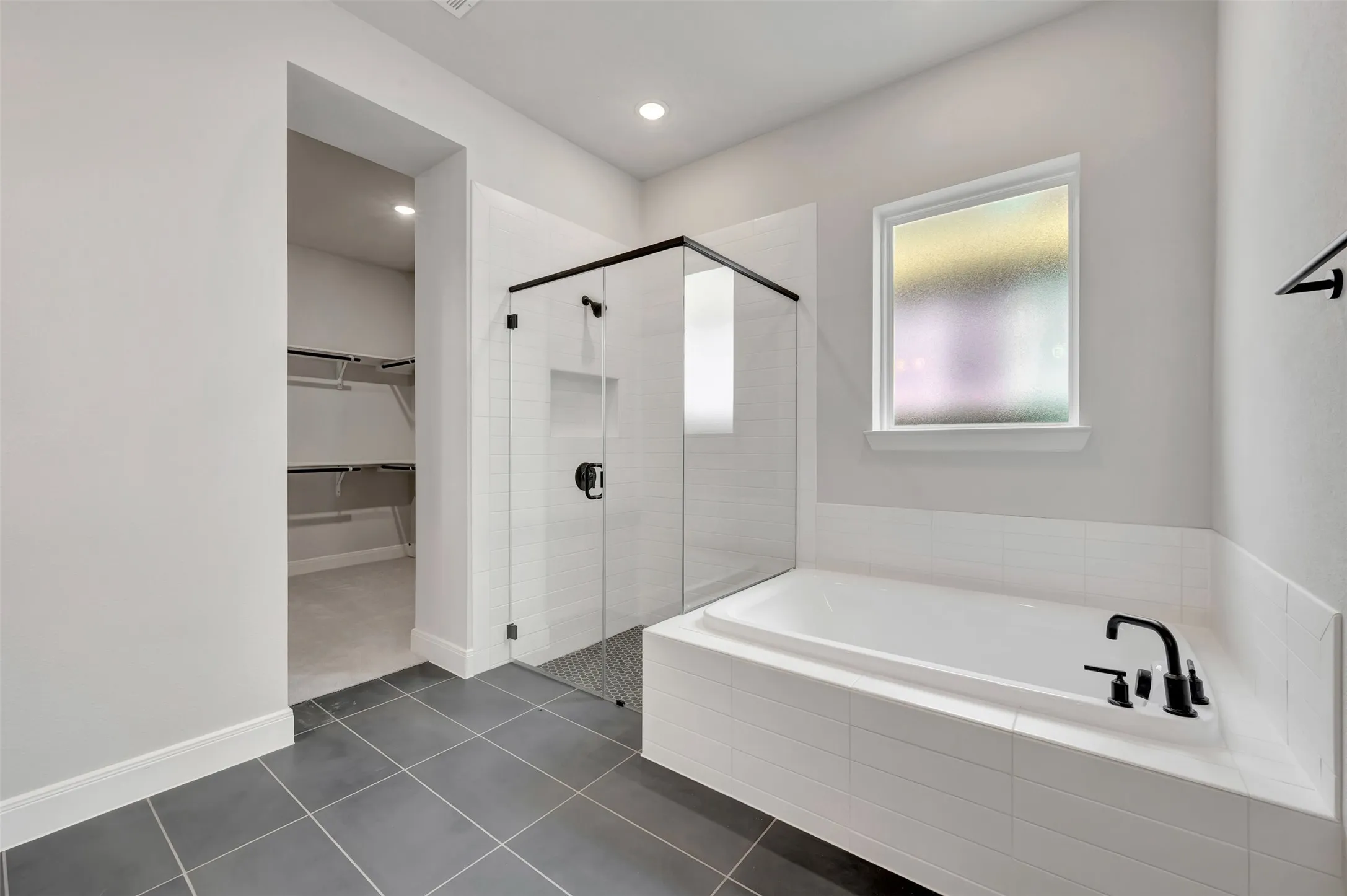 Full bath with a garden tub, a shower stall, a spacious closet, dark tile patterned flooring, and recessed lighting