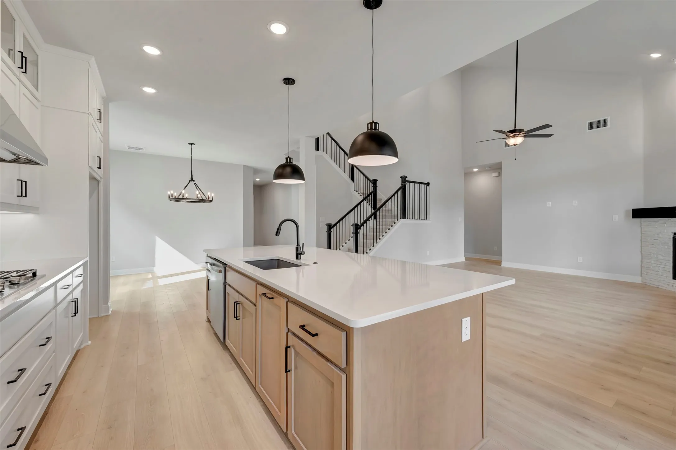 Kitchen with light wood-style flooring, open floor plan, a center island with sink, a fireplace, and dual tone cabinets