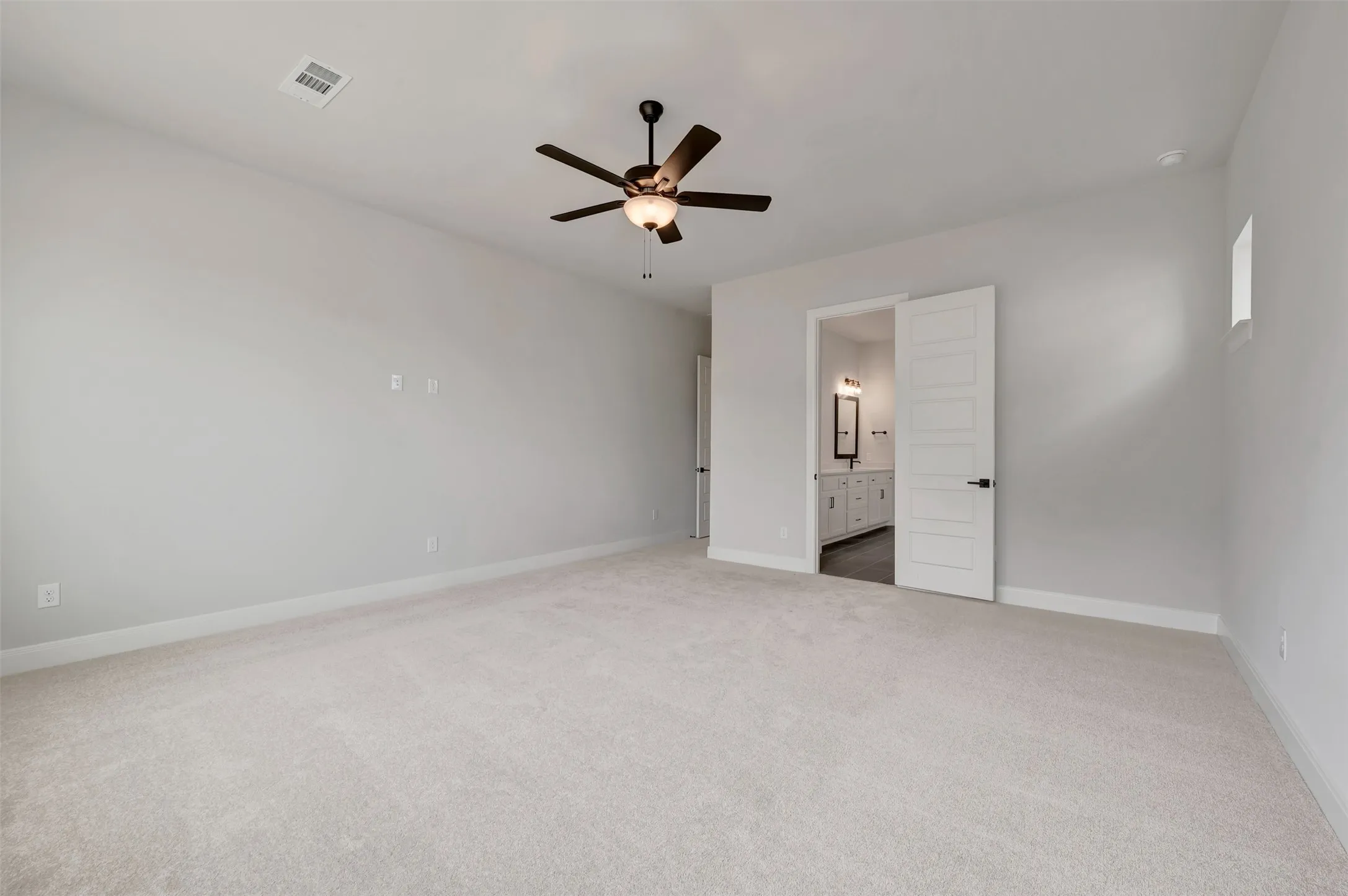 Unfurnished bedroom with light carpet, a ceiling fan, and ensuite bath
