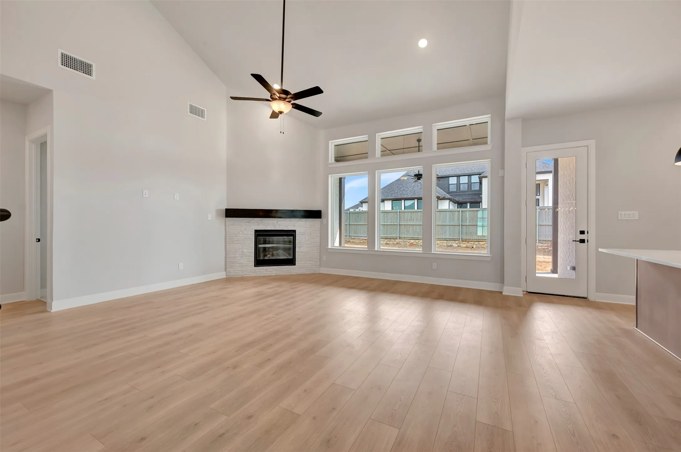 Unfurnished living room with lofted ceiling, a stone fireplace, a ceiling fan, light wood-style floors, and recessed lighting