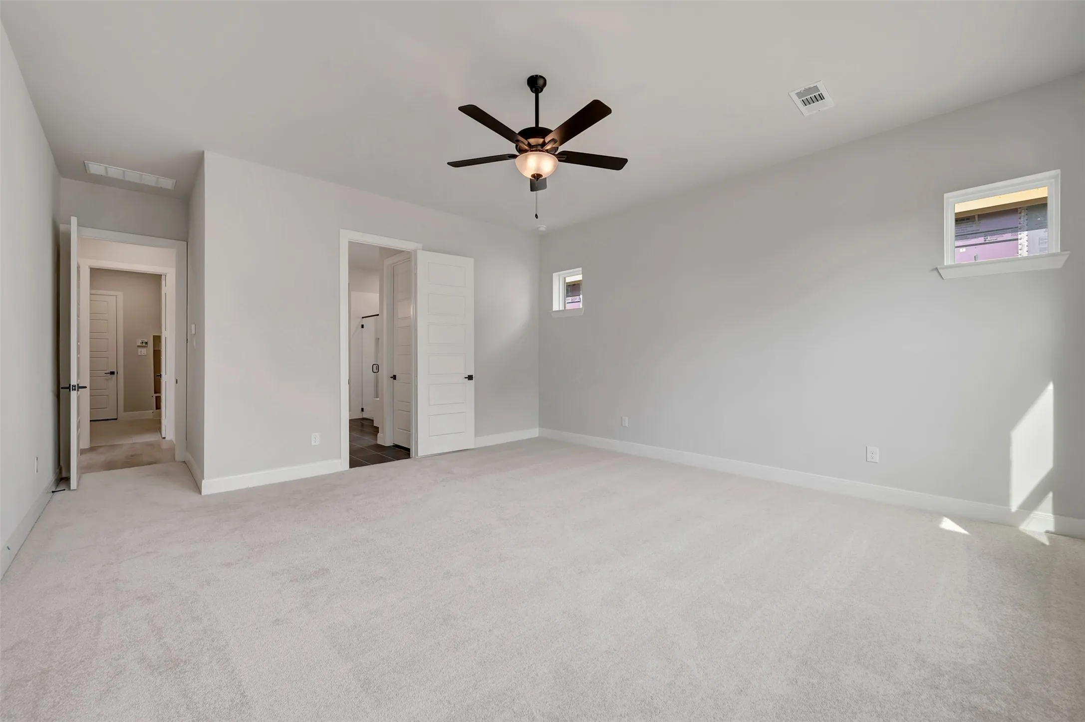Unfurnished bedroom with light carpet, ceiling fan, and multiple windows