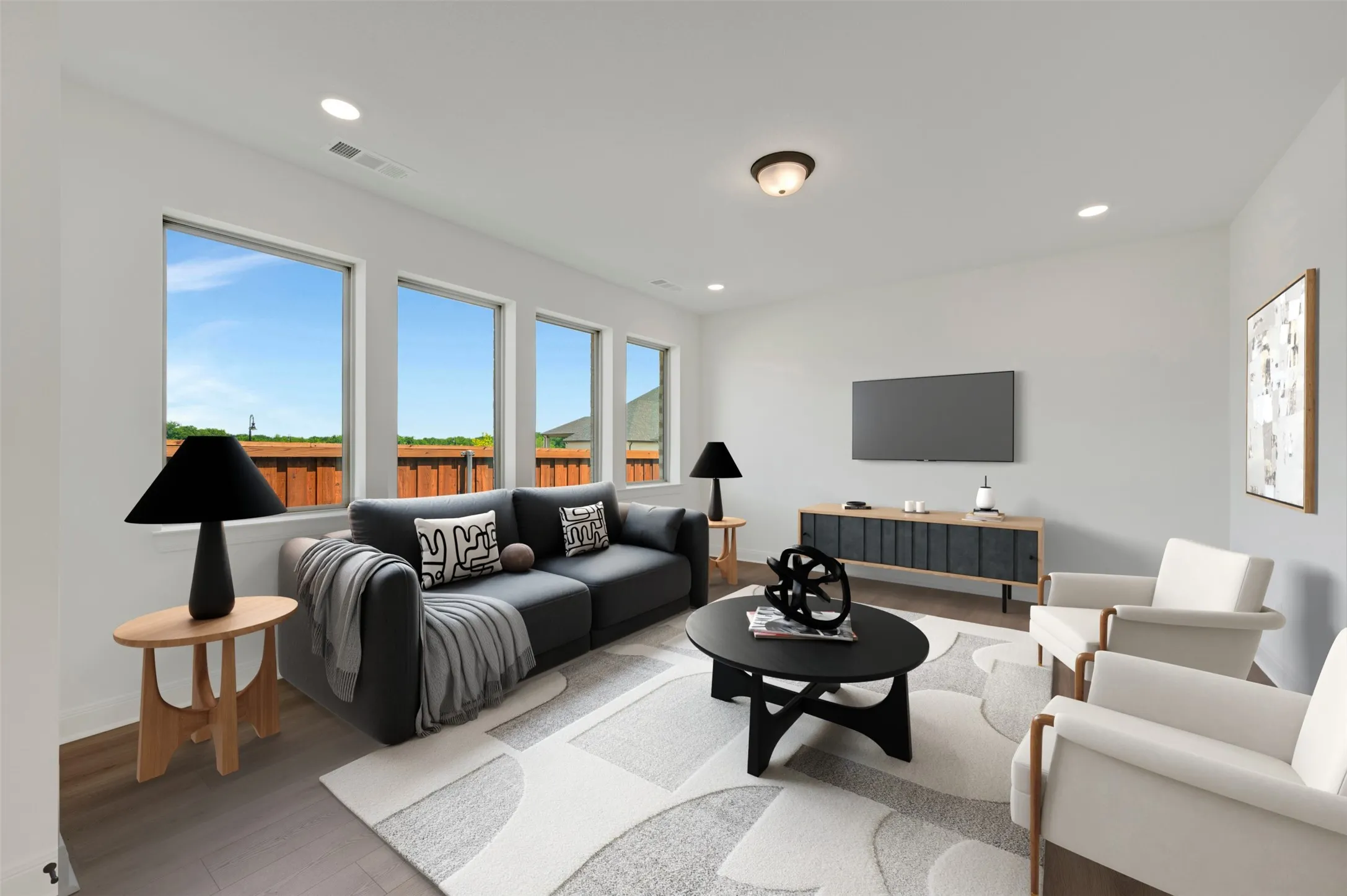 Living area featuring a row of four windows, recessed ceiling lighting, a ceiling-mounted light fixture, wood-finish flooring, and a mounted flat-screen television