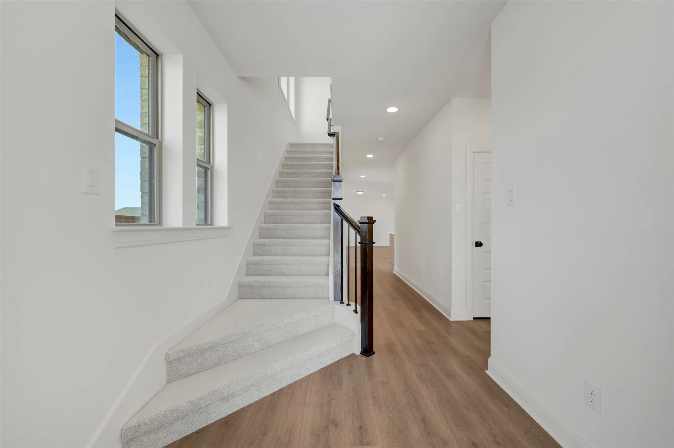 Carpeted staircase with dark wood-finish newel post and balusters