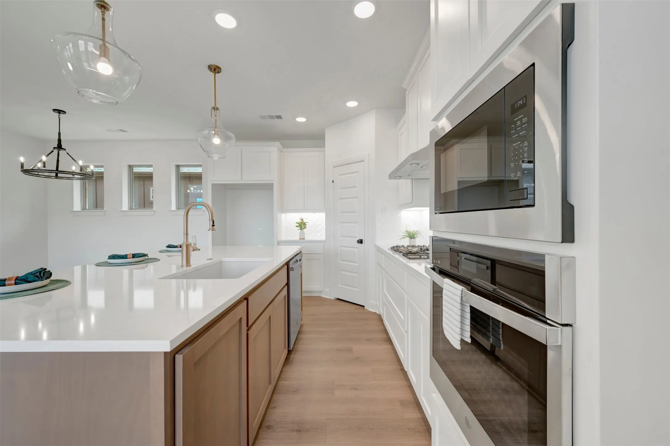 Contemporary kitchen featuring a large island with an undermount sink, quartz countertops, and wood-finish flooring