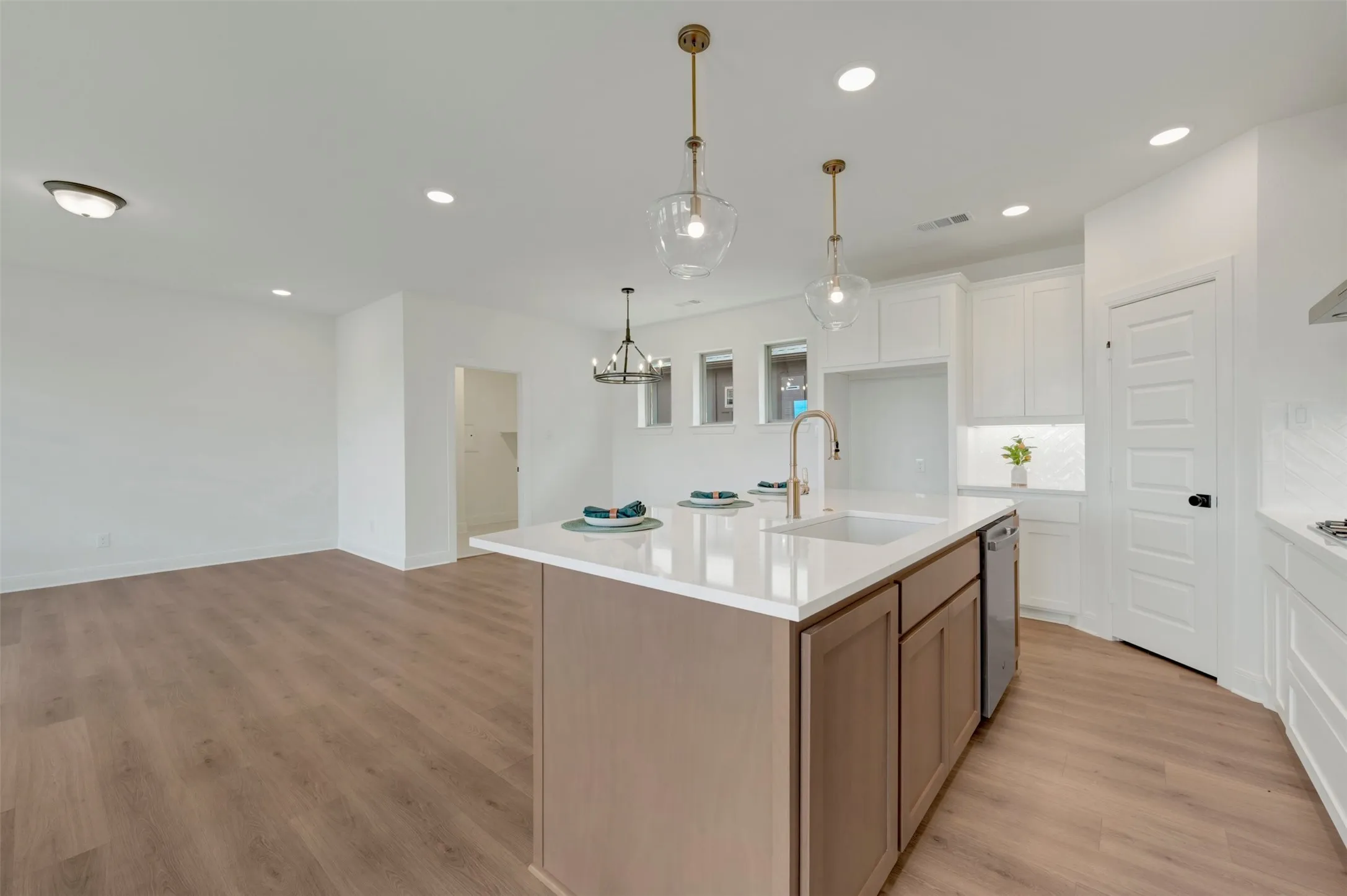 Kitchen island with a white countertop and integrated sink, accompanied by two clear glass pendant lights