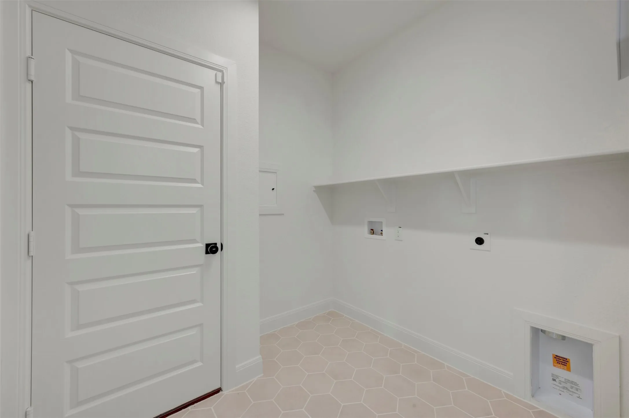 Utility room featuring honeycomb tile flooring, white walls, and a built-in storage shelf