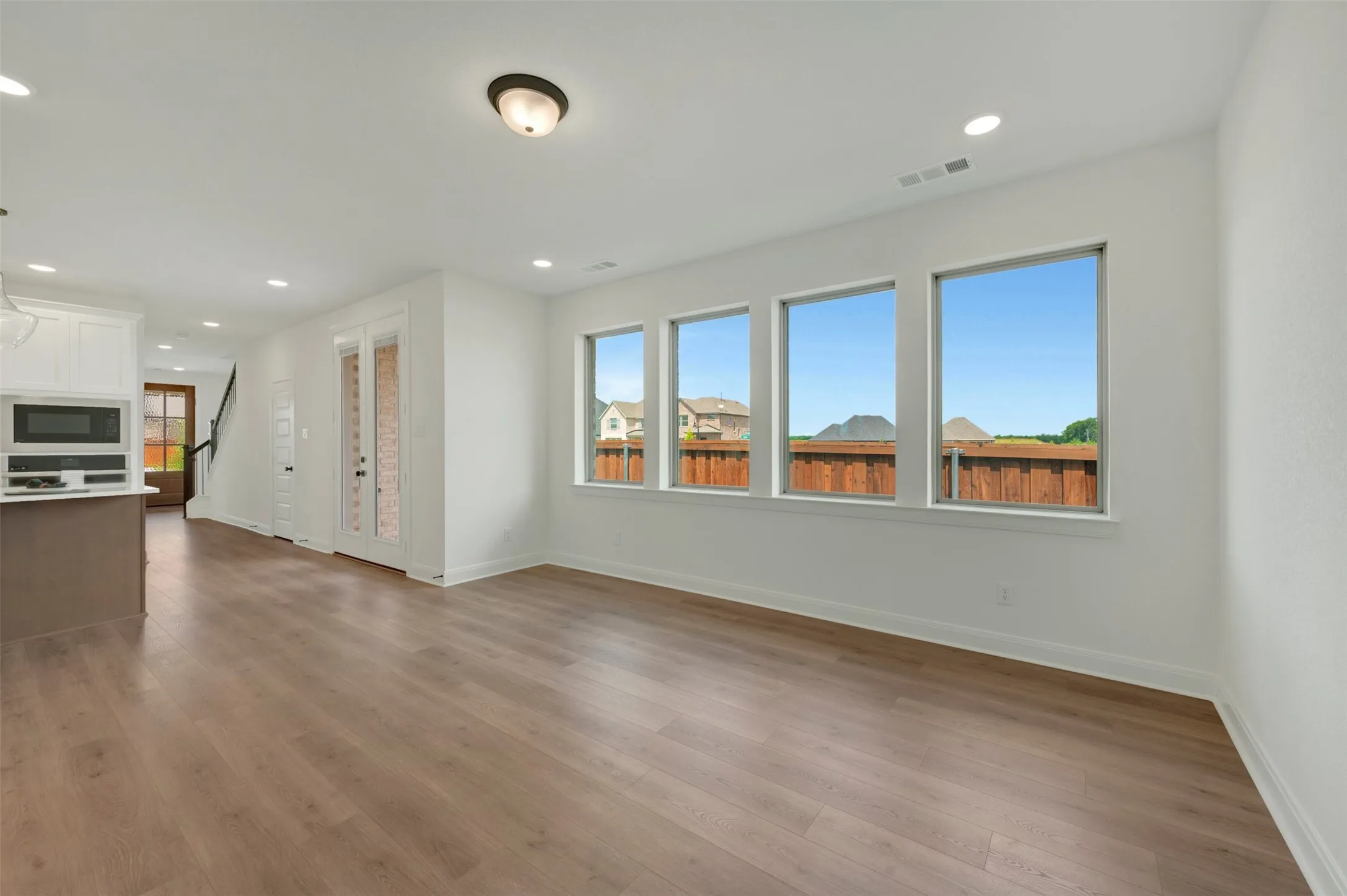 Open-concept living space featuring wood-finish flooring, recessed lighting, and a white color palette