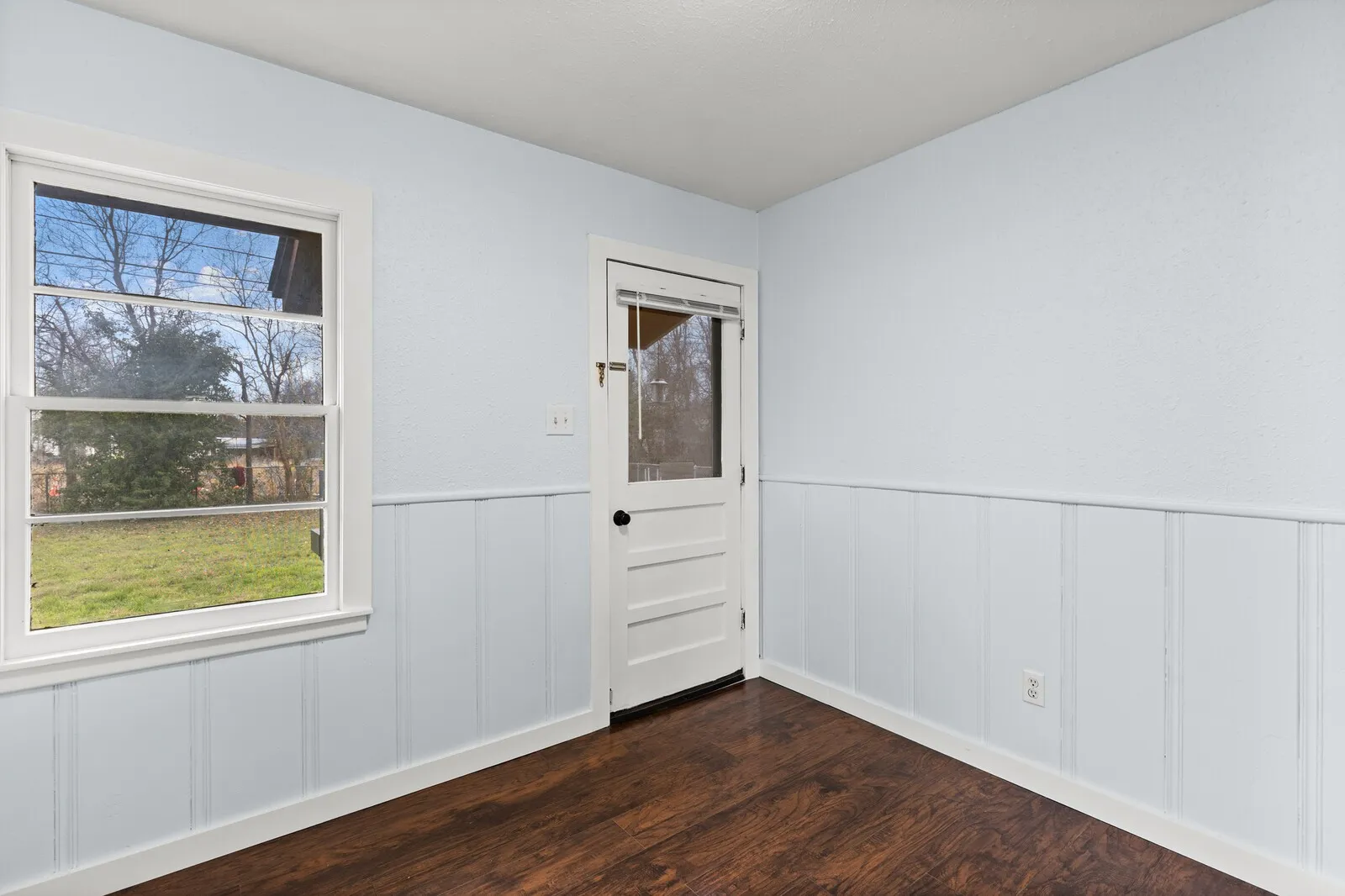 Empty room with a wainscoted wall, dark wood finished floors, and a decorative wall