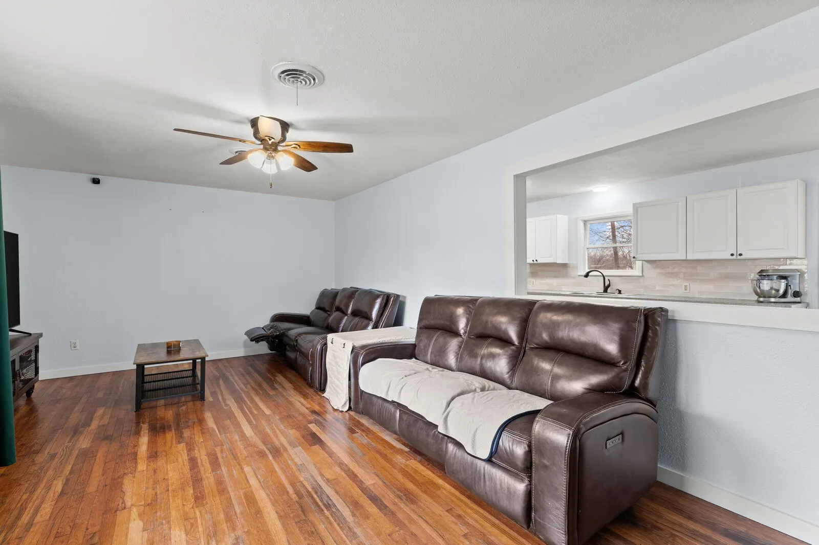 Living room with dark wood finished floors and a ceiling fan
