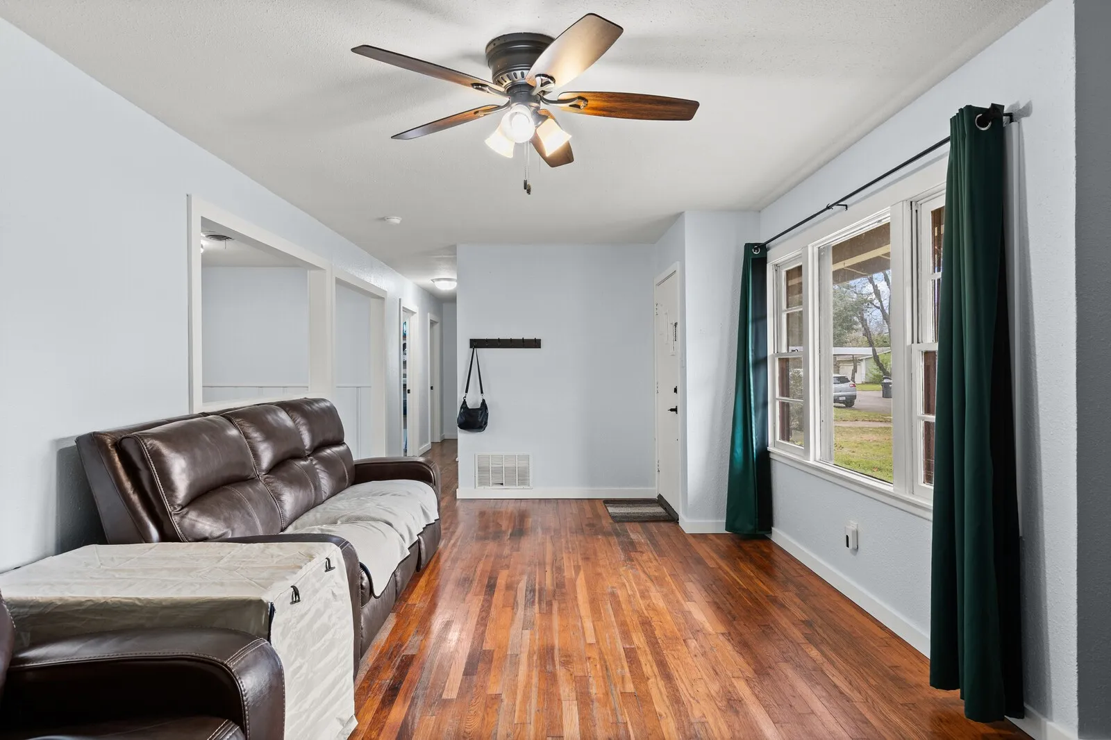 Living area with dark wood-style floors and ceiling fan