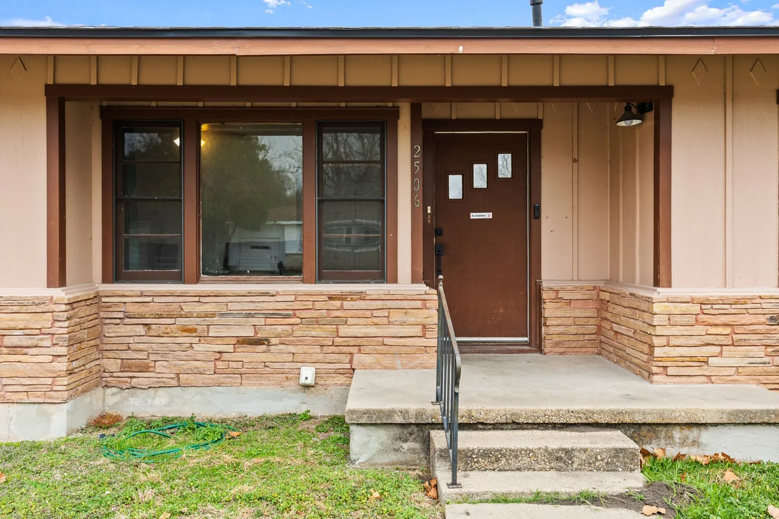 Property entrance with a porch, brick siding, and board and batten siding