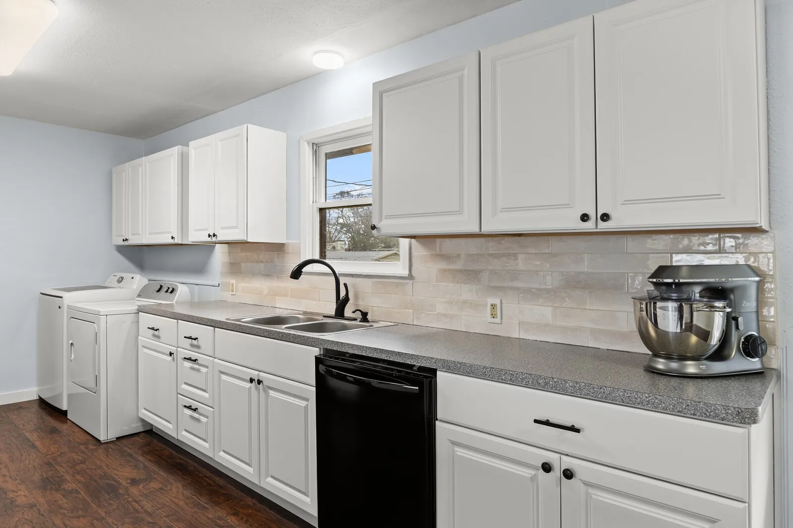 Kitchen with black dishwasher, white cabinets, separate washer and dryer, tasteful backsplash, and dark wood finished floors