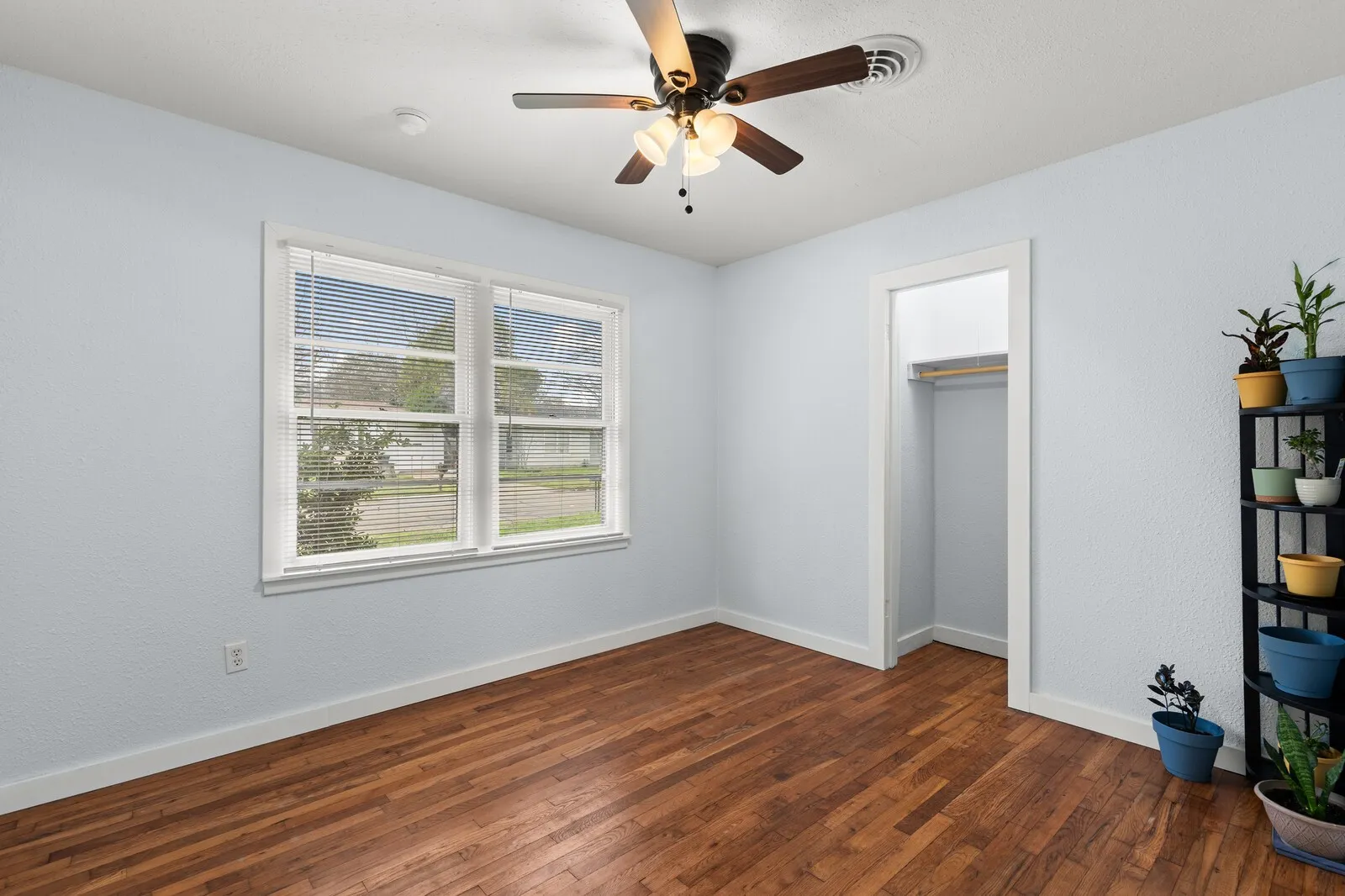 Unfurnished bedroom featuring a ceiling fan, dark wood-style floors, and a closet