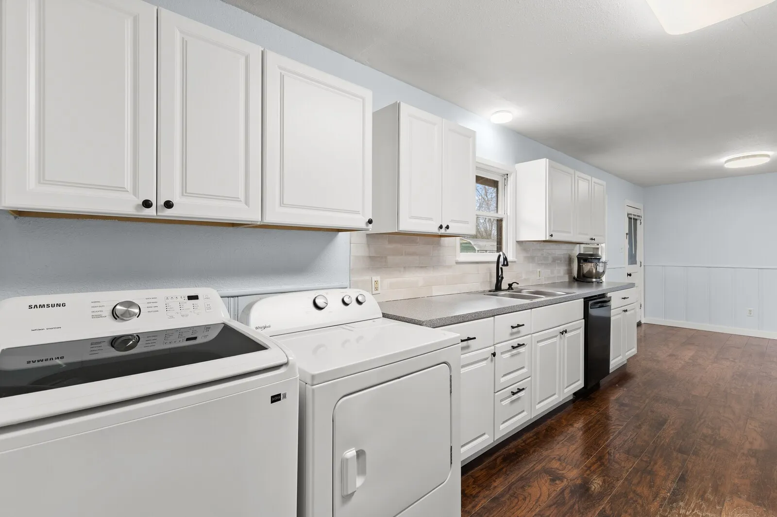 Laundry area with dark wood-style floors, wainscoting, and separate washer and dryer