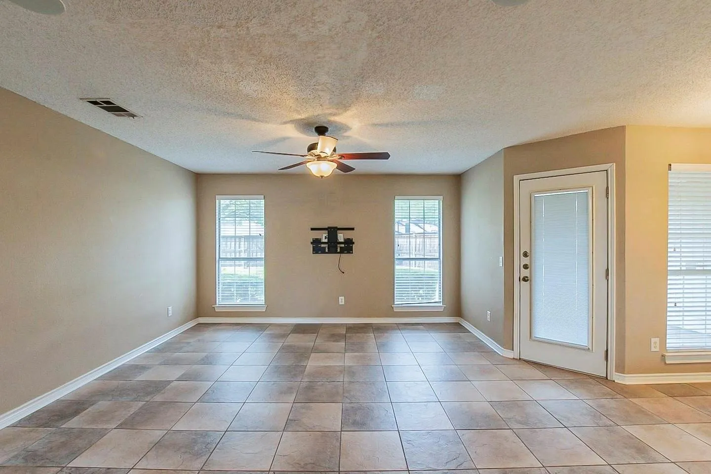 Unfurnished room featuring healthy amount of natural light, a textured ceiling, and ceiling fan
