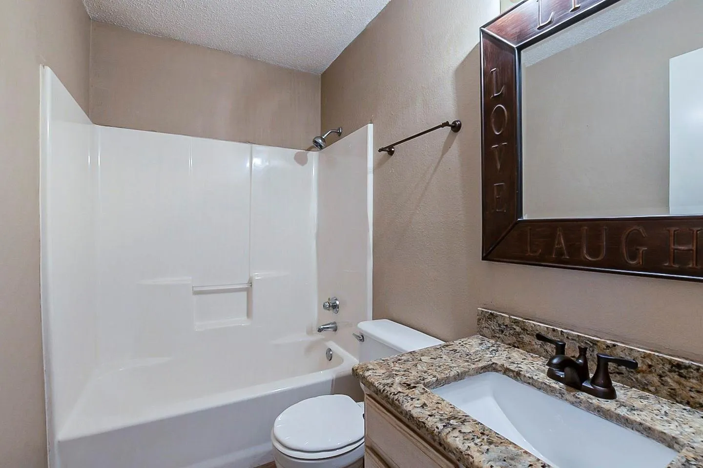 Full bath with a textured ceiling, tub / shower combination, vanity, and a textured wall