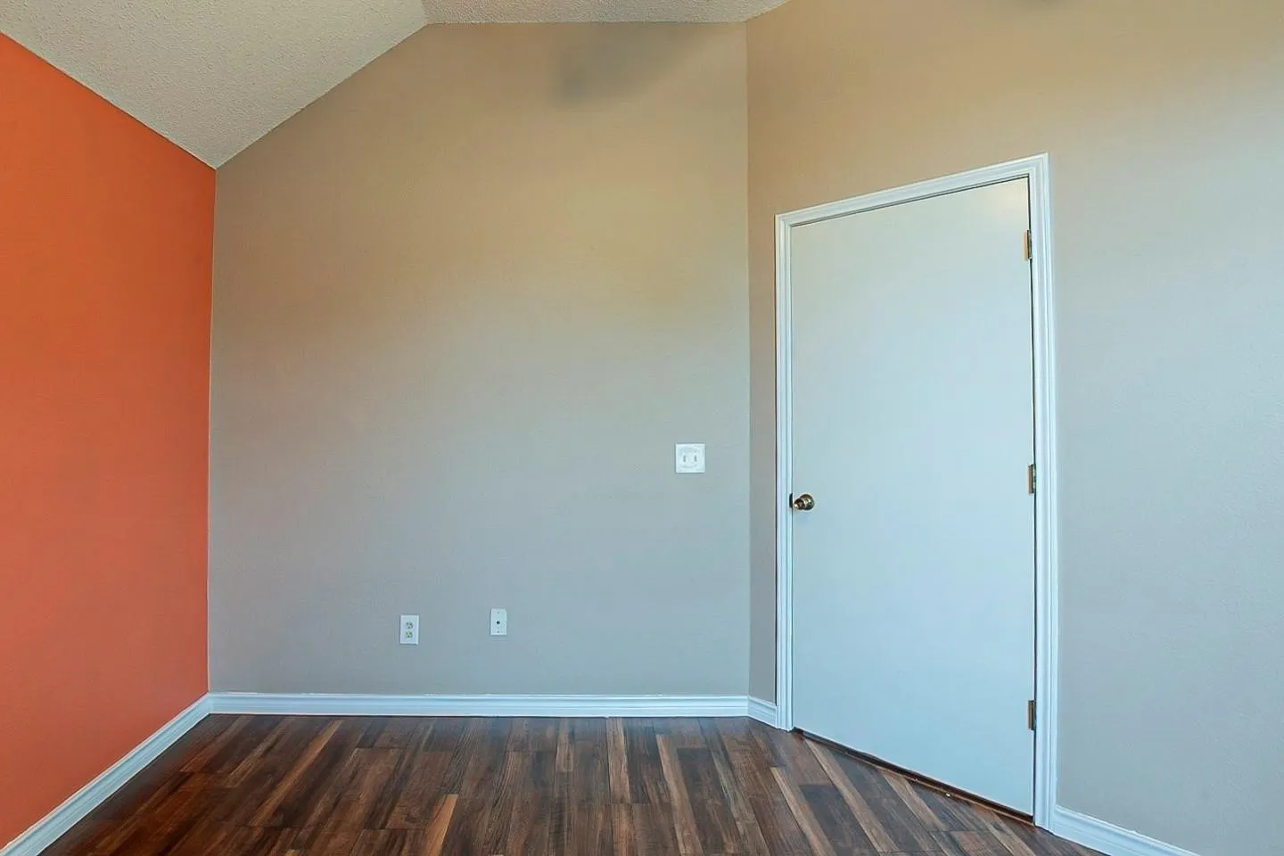 Unfurnished room featuring vaulted ceiling, dark wood finished floors, and a textured ceiling