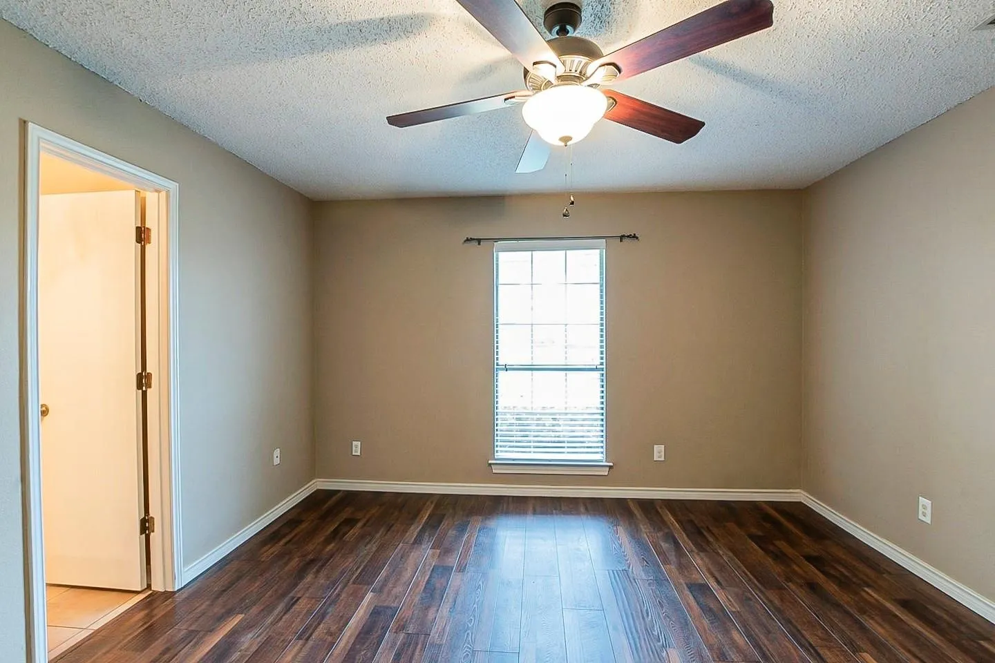 Unfurnished room featuring dark wood-type flooring, a textured ceiling, and ceiling fan