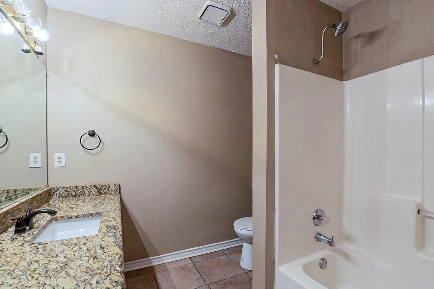 Full bathroom featuring vanity, a textured ceiling, light tile patterned flooring, and bathing tub / shower combination