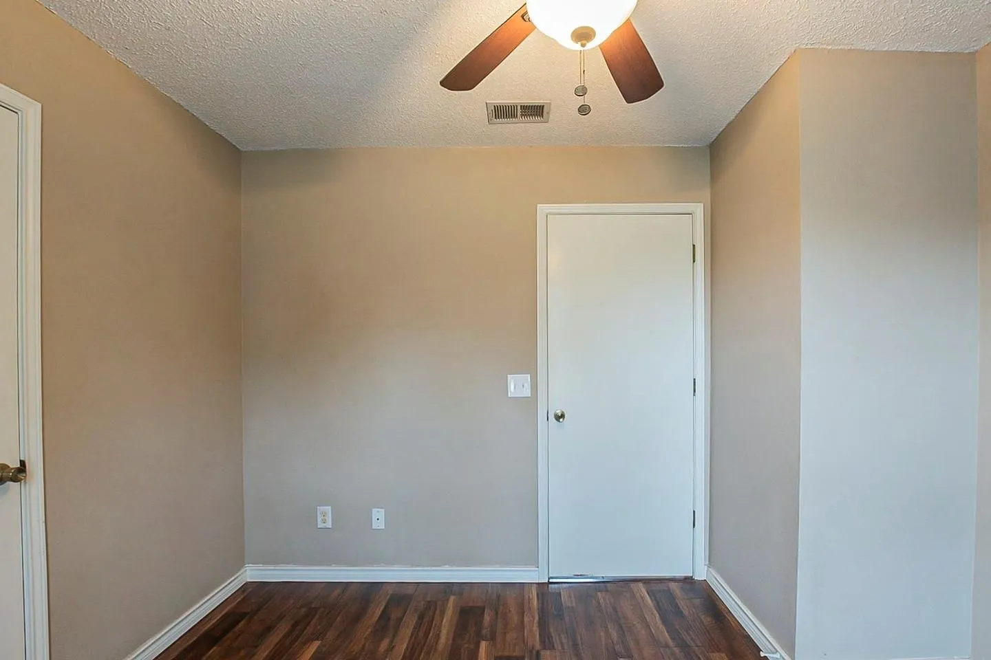 Spare room with dark wood-type flooring, a textured ceiling, and a ceiling fan