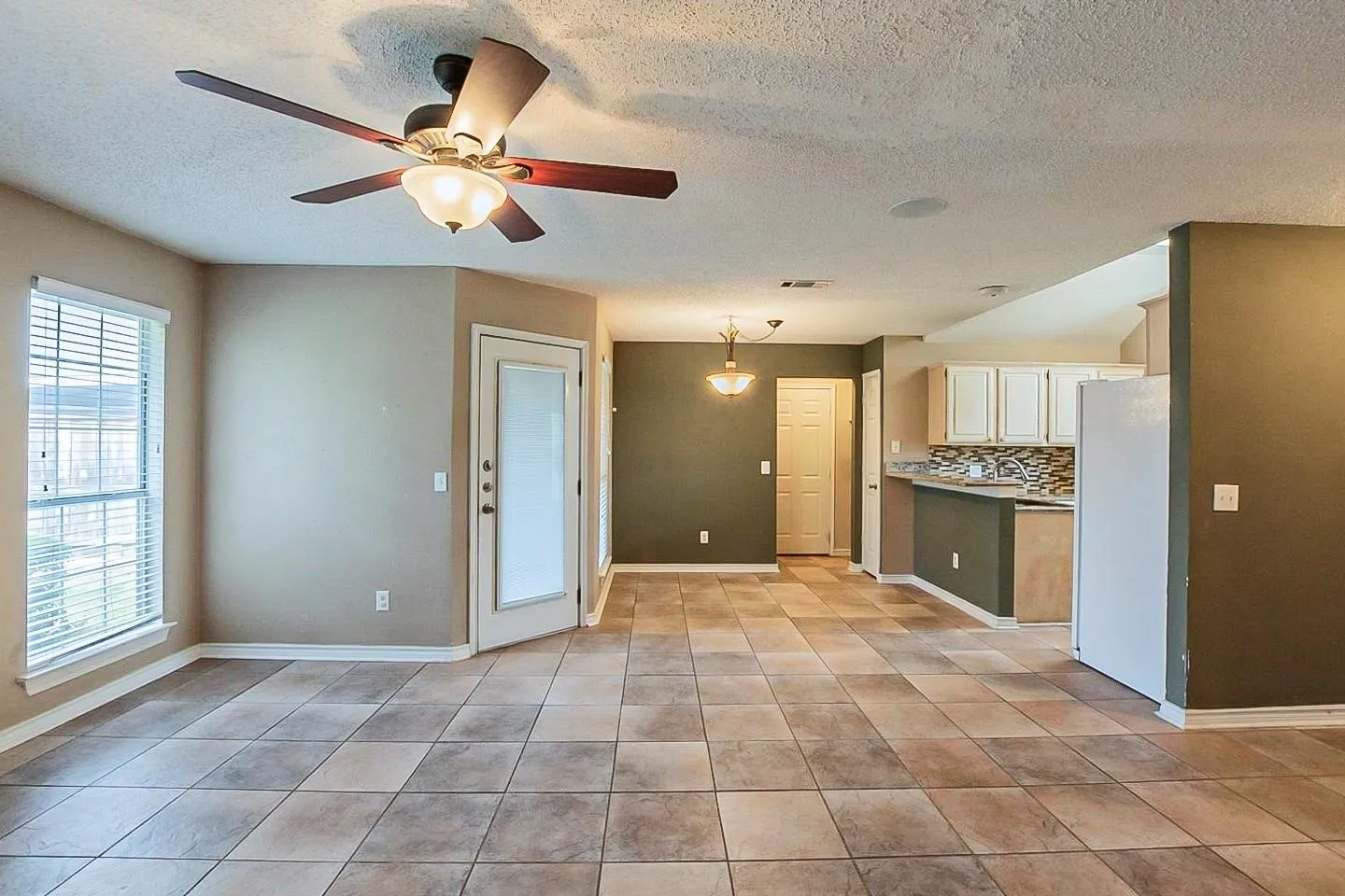 Kitchen with freestanding refrigerator, a textured ceiling, light countertops, ceiling fan, and pendant lighting