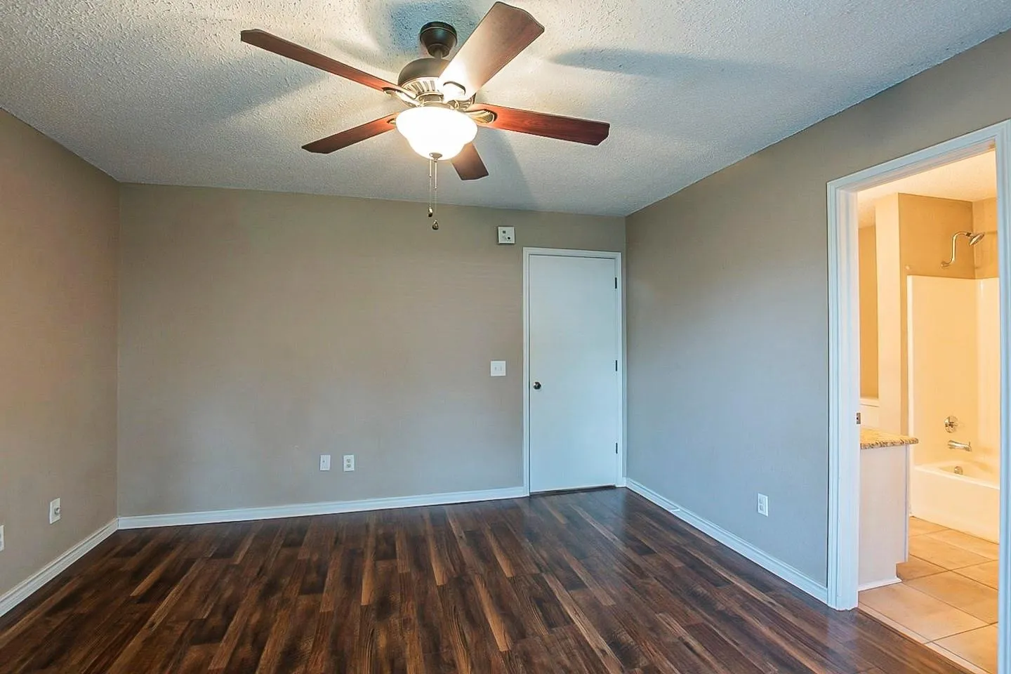 Spare room with a textured ceiling, dark wood-style flooring, and ceiling fan