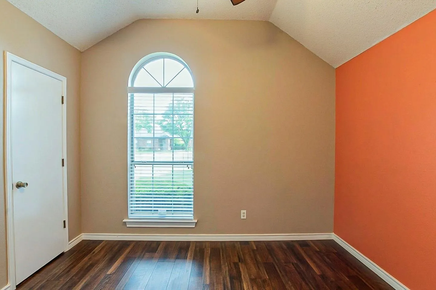 Spare room with dark wood-style flooring, vaulted ceiling, a ceiling fan, and a textured ceiling