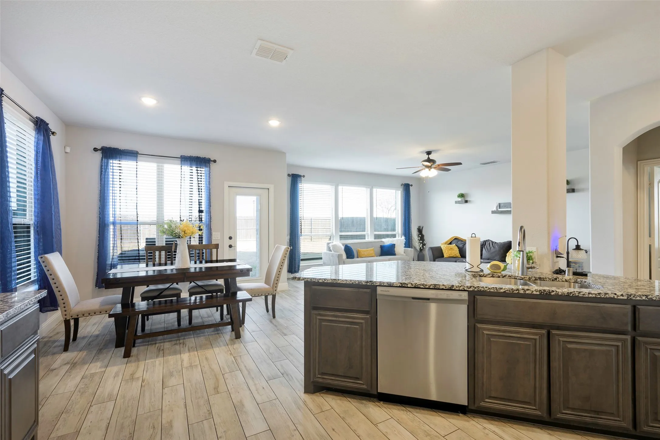 Kitchen featuring dark brown cabinets, stainless steel dishwasher, light stone countertops, light wood finished floors, and recessed lighting